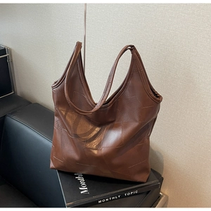 Close-up of brown vintage tote bag featuring geometric patchwork and matte leather texture