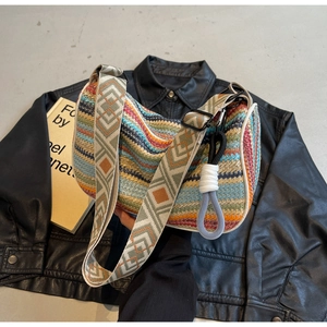 Detail of colorful woven hobo bag with geometric patterned strap on leather jacket
