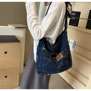 Detail einer dunkelblauen Denim-Einkaufstasche mit THE MONSTERS Stickerei und Vintage-Tasche