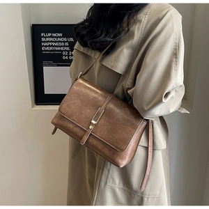 Macro detail of the brown PU leather crossbody bag featuring a metallic silver bar lock
