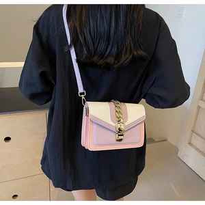 Detail view of stylish color-block crossbody bag with gold chain and purple strap
