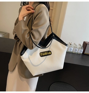 Detail of white pleated tote bag with black contrast trim and Fashion logo patch