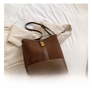 Brown bucket bag detail showing suede and smooth leather texture with gold buckle lock