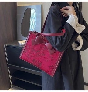 Close-up of red floral lace embroidery and elegant bow detail on luxury bridal tote bag
