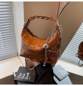 Detail of caramel quilted leather bag with silver chain and decorative metal ball charm
