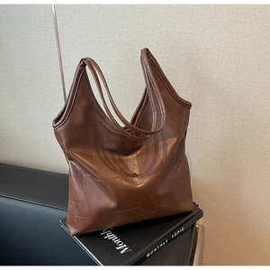 Detailed close-up of brown textured leather tote bag with geometric patchwork design