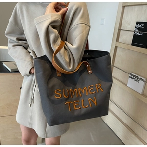 Détail du grand sac cabas en toile grise avec broderie orange et anses en cuir