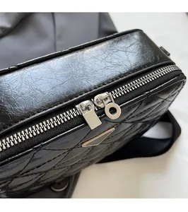 Detail of black quilted leather camera bag with silver dual zippers and diamond pattern