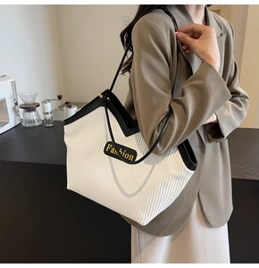 Close-up of contrast large tote bag featuring cream pleated texture and black trim details