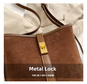 Detail of golden metal twist lock on brown faux suede crossbody bag with leather trim
