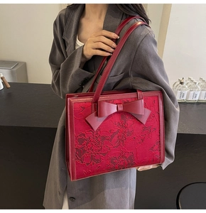 Close-up of wine red bridal handbag with floral embroidery and large leather bow detail