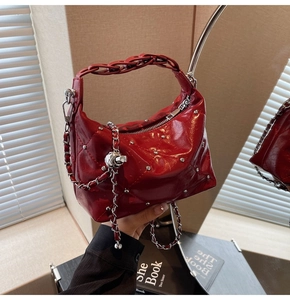 Detail of red quilted leather handbag with silver studs and chain with ball charm