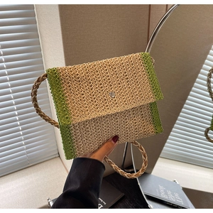 Dettaglio della borsa a busta in paglia con bordo verde a contrasto e chiusura magnetica