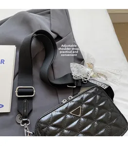 Detail of black quilted leather camera bag with adjustable wide fabric shoulder strap
