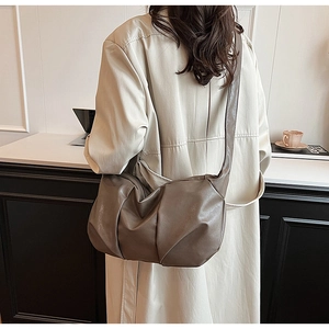 Detail of dark taupe pleated shoulder bag in soft leather texture on a female model