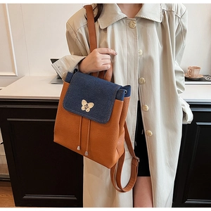 Detail of contrast backpack with blue denim flap and orange lychee leather texture