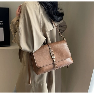 Detail of vintage brown leather crossbody bag with elegant gold buckle on a long strap