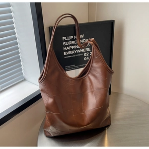 Close-up of dark brown tote bag showing textured leather and square stitching details