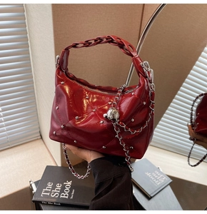 Detail of dark red quilted leather bag with silver studs and woven handle texture