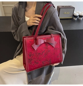 Detail of red bridal tote bag featuring intricate floral embroidery and leather bow