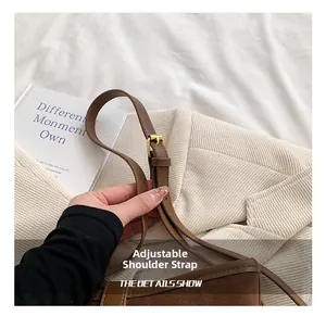 Close-up of adjustable shoulder strap with gold buckle on brown faux suede crossbody bag