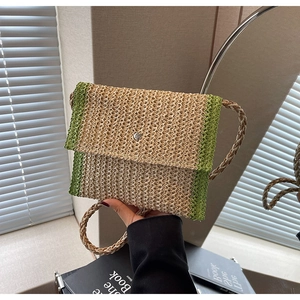 Dettaglio della borsa a busta in paglia intrecciata con contrasto verde e bottone