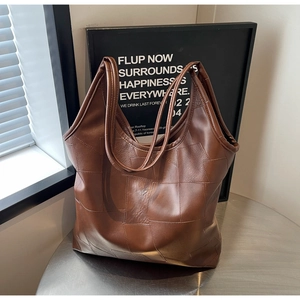 Detail of a brown patchwork tote bag with square panels on a silver metal table
