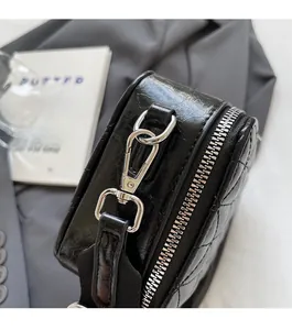 Detailed macro view of silver metal zipper and D-ring on black quilted leather bag