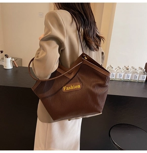 Detail view of coffee-colored pleated tote bag with fashion tag on textured synthetic leather