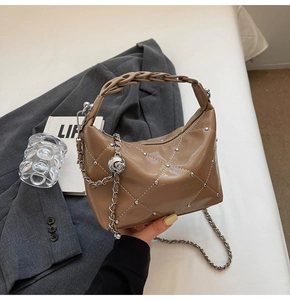 Close-up of khaki quilted leather bag with silver rivets and metal rose charm detail