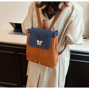 Detail of the brown leather backpack with blue denim flap and gold butterfly clasp buckle