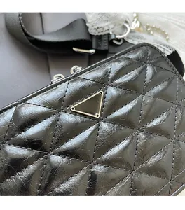 Detail of black quilted leather camera bag with metallic triangle logo and strap