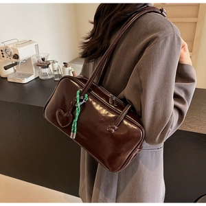 Détail du sac bowling vintage marron chocolat en cuir avec breloque cœur et cordon tressé
