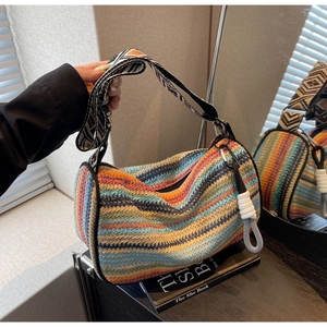 Detail of colorful rainbow woven bag featuring a wide jacquard strap and side knot detail