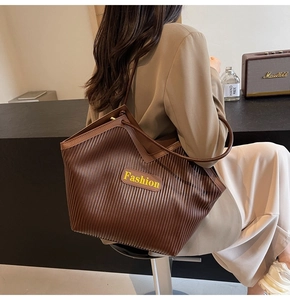 Detailed view of brown pleated tote bag featuring a prominent yellow Fashion label detail