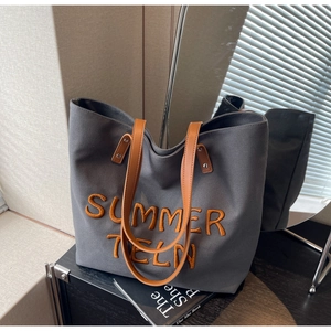 Détail du sac cabas en toile grise avec broderie orange et bandoulières en similicuir