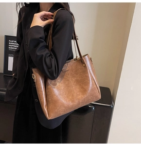 Détail d'un grand sac cabas vintage marron montrant le cuir texturé et la boucle dorée