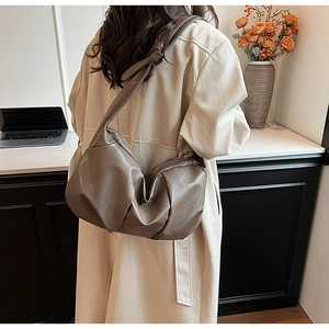 Detail of taupe ruched hobo bag featuring a unique knotted strap and soft leather texture