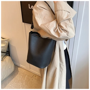 Detail of black lychee grain leather bucket bag with wide strap and subtle logo embossing