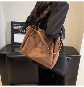 Sac cabas vintage en similicuir marron avec fine bandoulière porté par un mannequin