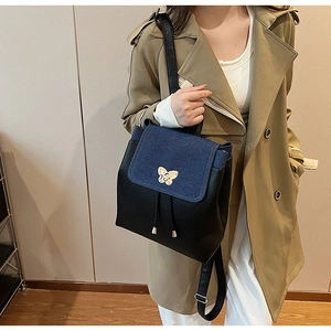 Detail of color-block backpack with butterfly clasp and denim flap on trench coat
