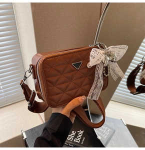 Detailed view of brown quilted faux leather camera bag with wide strap and cute bear charm