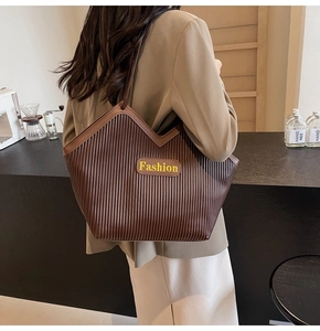 Detail of dark brown pleated tote bag with Fashion patch shown on a model