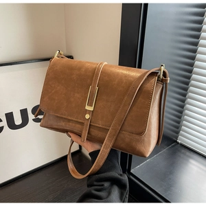 Macro shot of brown faux leather texture and gold buckle on a retro crossbody bag