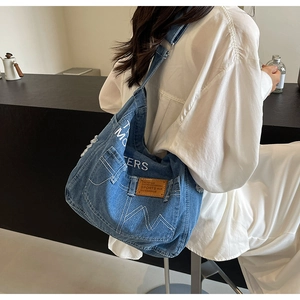 Detailansicht der blauen Denim-Tragetasche mit weißer Stickerei und Kontrastnähten