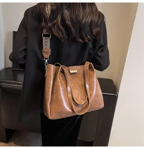 Détail d'un grand sac cabas en cuir marron avec une bandoulière tissée ethnique décorative