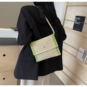 Dettaglio della borsa a busta in paglia intrecciata beige e verde a tracolla