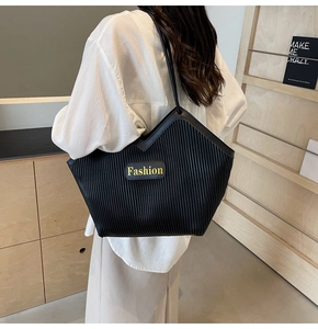 Close-up of black pleated tote bag with vertical texture and Fashion leather tag