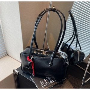 Détail du sac bowling en cuir verni noir avec fermeture éclair argentée et breloque coeur