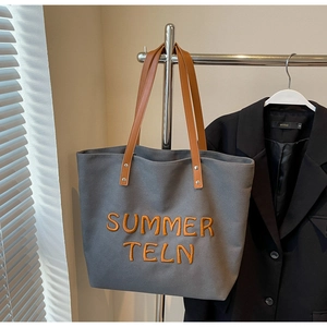 Détail du cabas en toile grise avec broderie SUMMER TELN orange et anses en cuir